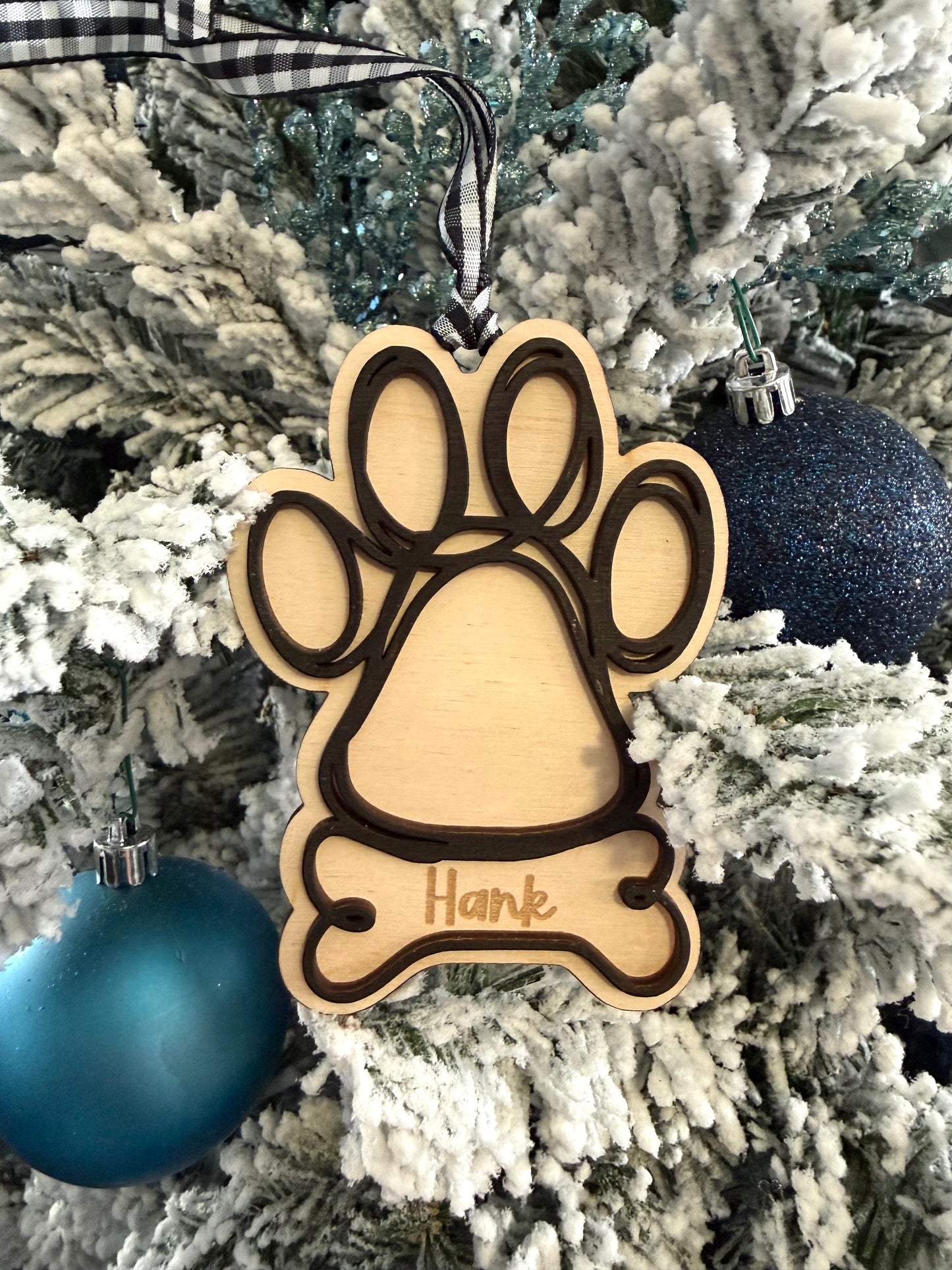 Decorative ornament with paw print and bone design on a Christmas tree.