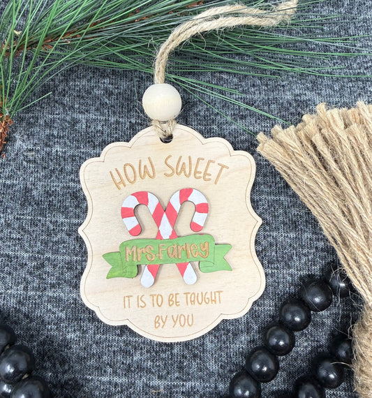 Decorative Christmas tag with candy canes and text on a textured surface with greenery and twine.
