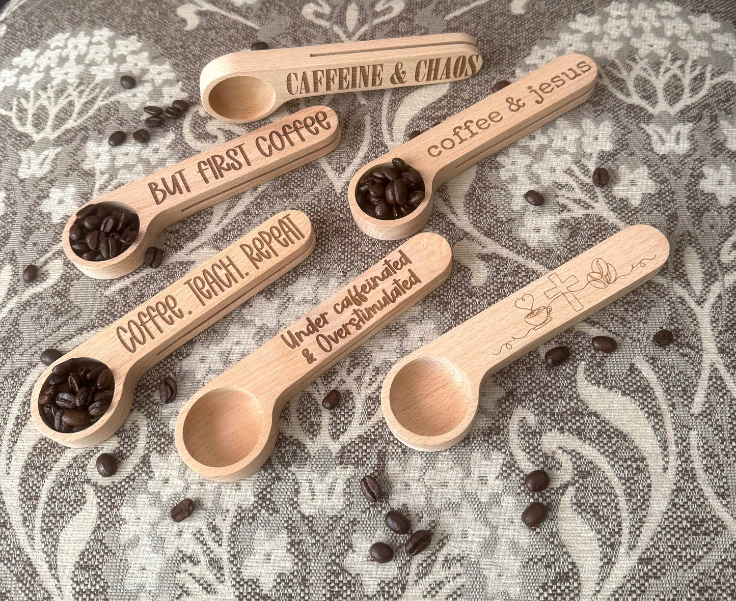Wooden spoons with coffee beans and engraved text on a floral fabric background