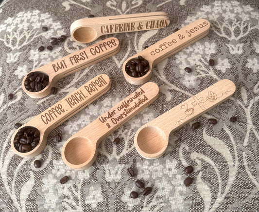 Wooden spoons with coffee beans and engraved text on a floral fabric background