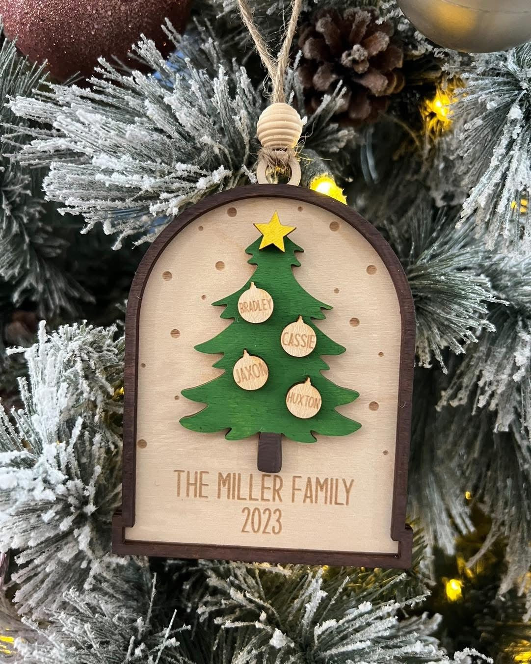 Christmas tree ornament with a family name and year on a decorated tree.