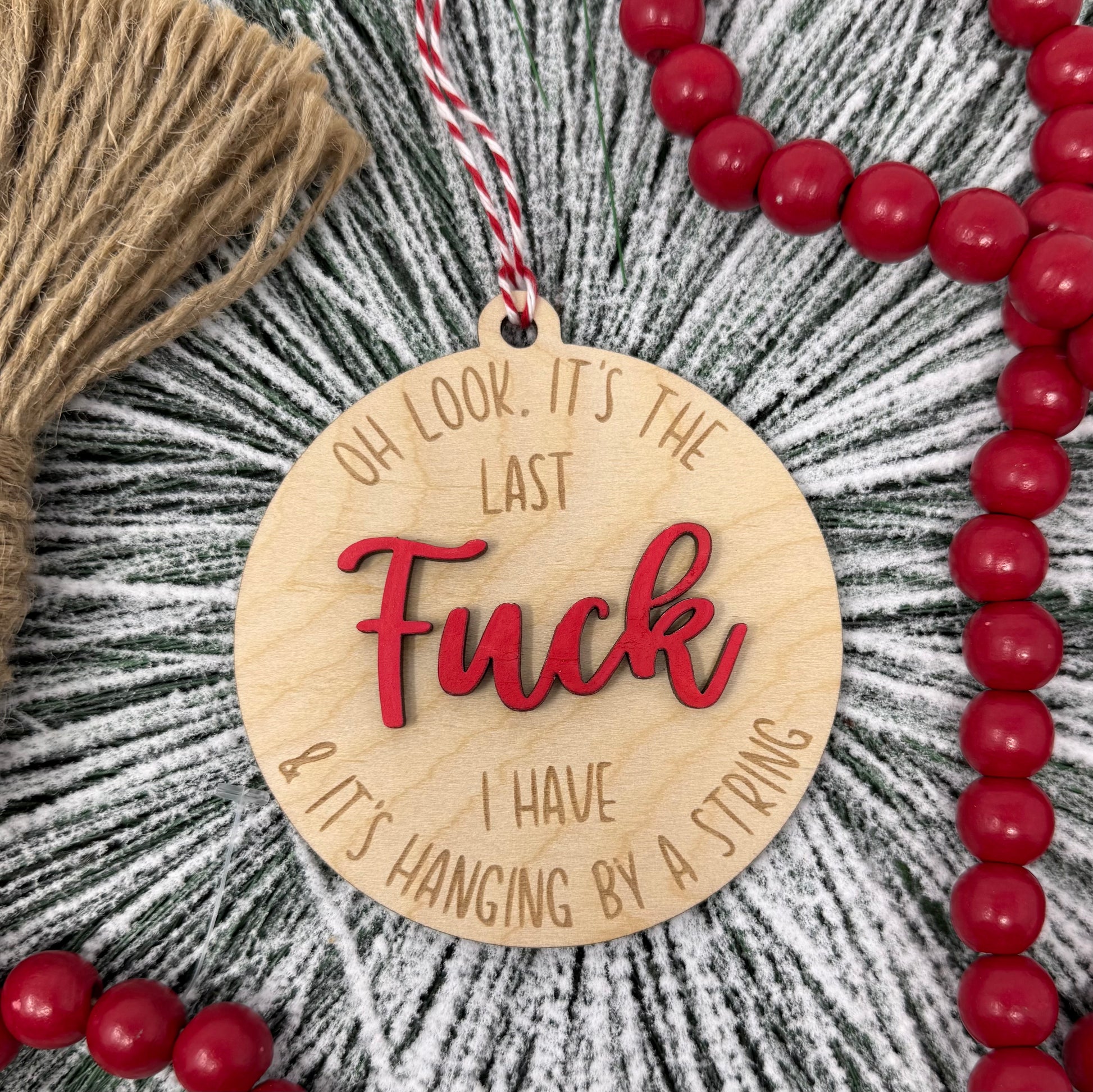 Wooden ornament with red text and beads on a textured background