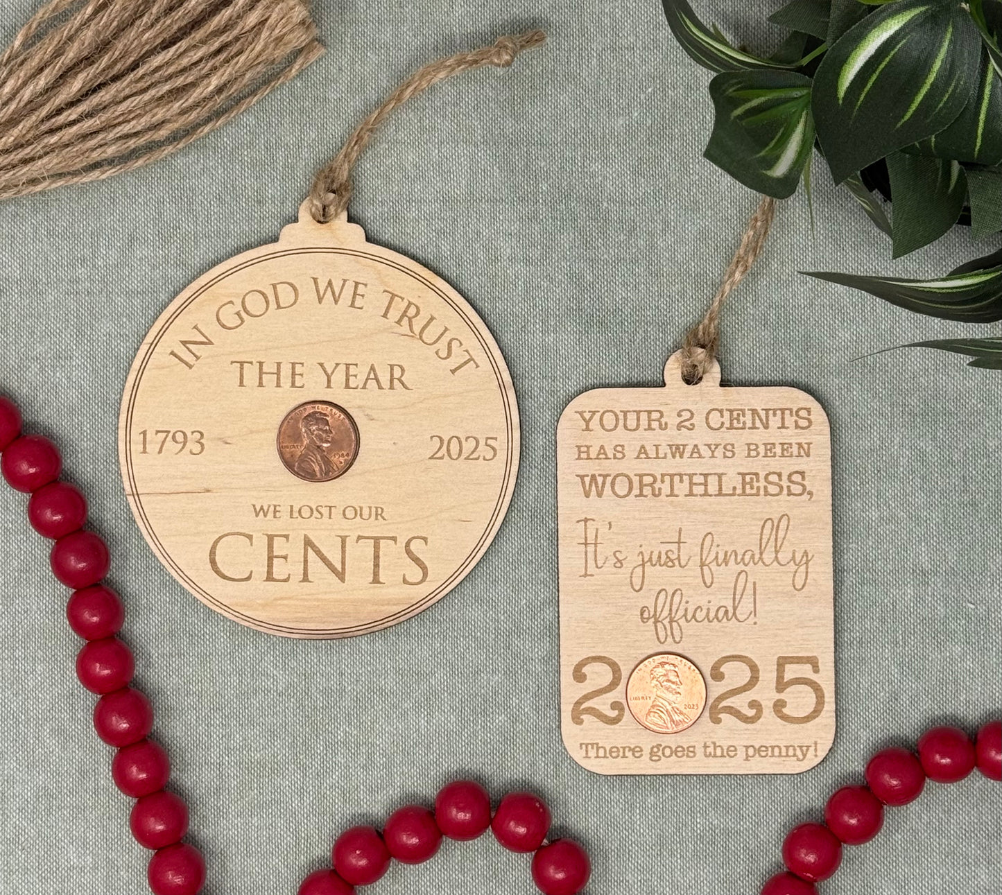 Two wooden ornaments with humorous text on a textured surface with red beads and green leaves.