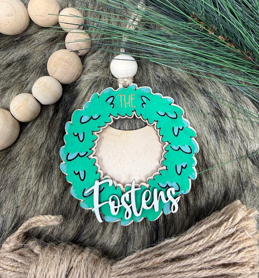 Decorative ornament with 'Fosters' text on a green wreath, surrounded by wooden beads and greenery.