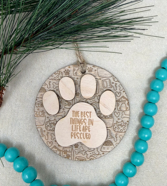 Decorative ornament with paw print design and text, surrounded by turquoise beads and pine branches.