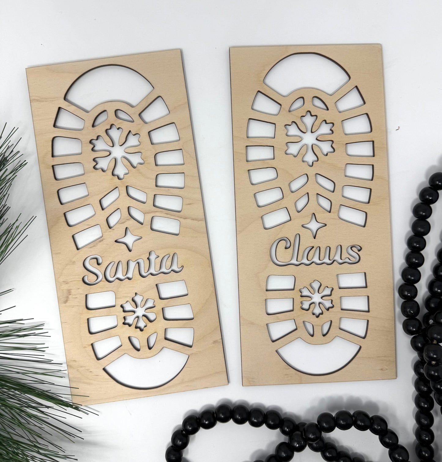 Two wooden Christmas decorations with cut-out patterns and 'Santa Claus' text on a white background.