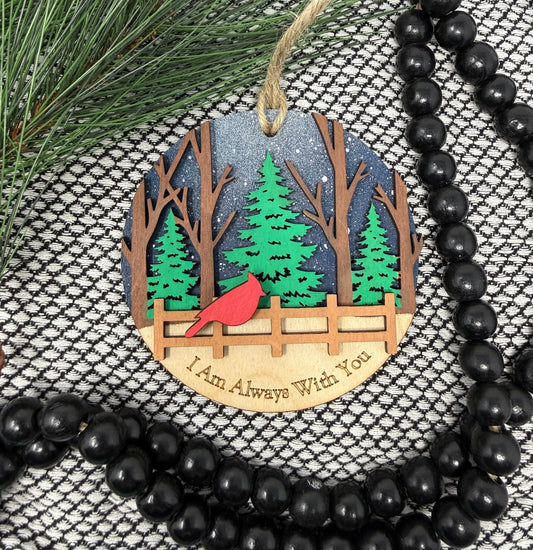 Decorative ornament with trees, cardinal, and engraved text on a textured surface with greenery and beads.